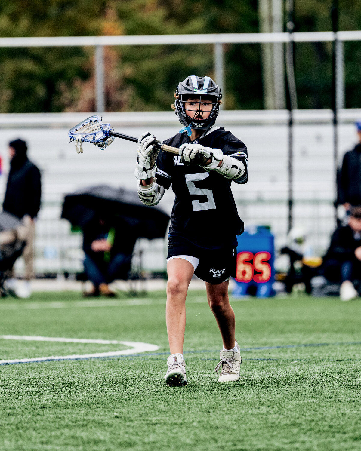 A club lacrosse player carrying the ball upfield.
