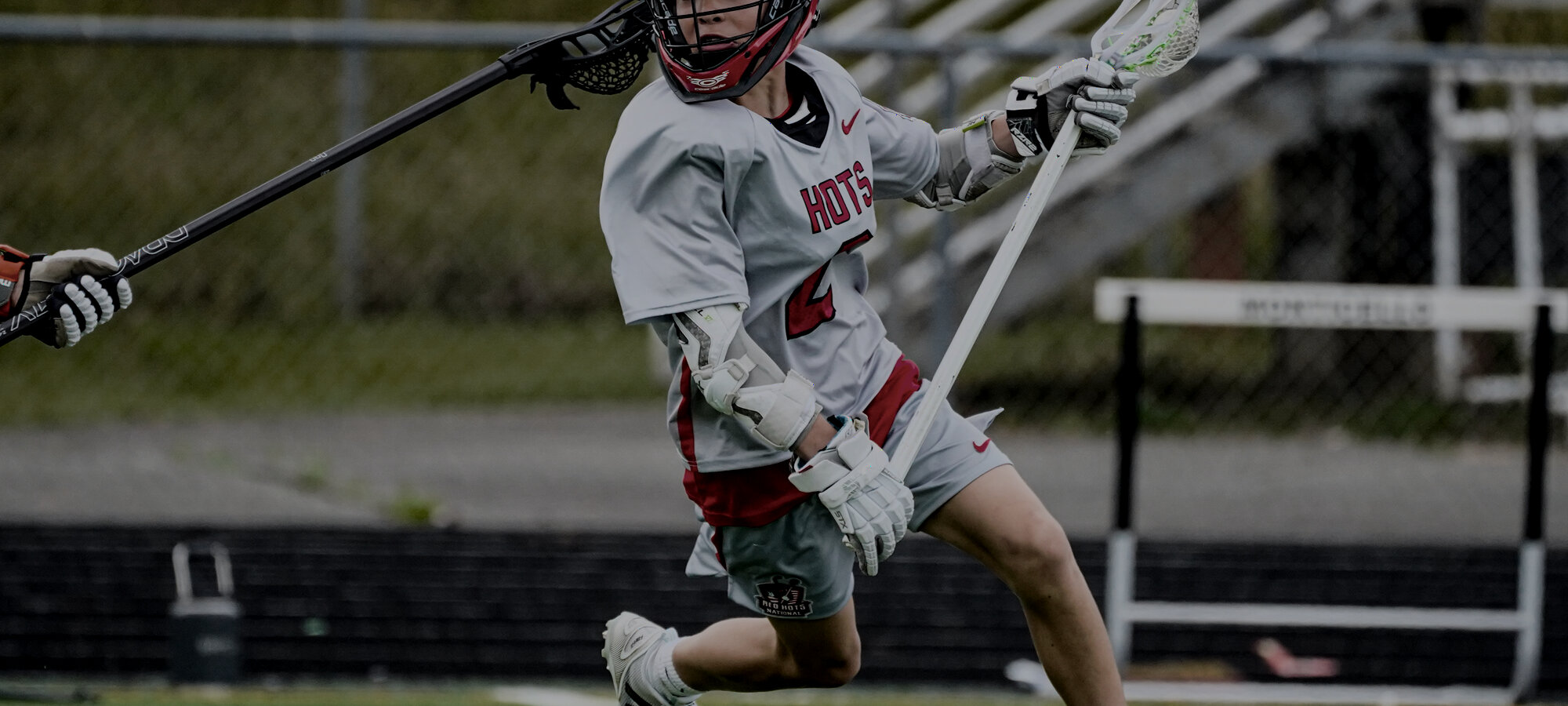 A club lacrosse player driving toward the goal.