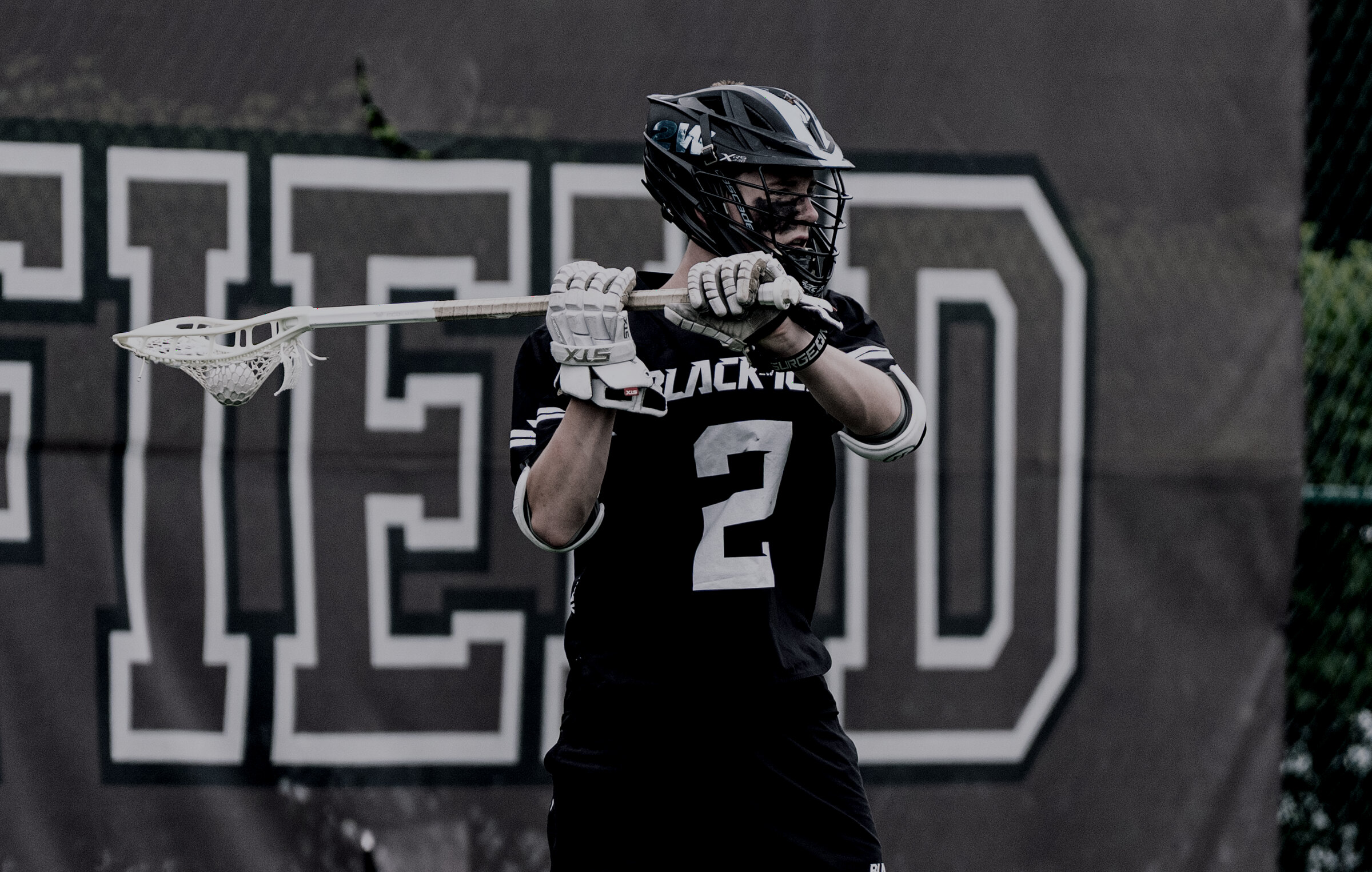 A club lacrosse player in a black helmet and jersey before a game.
